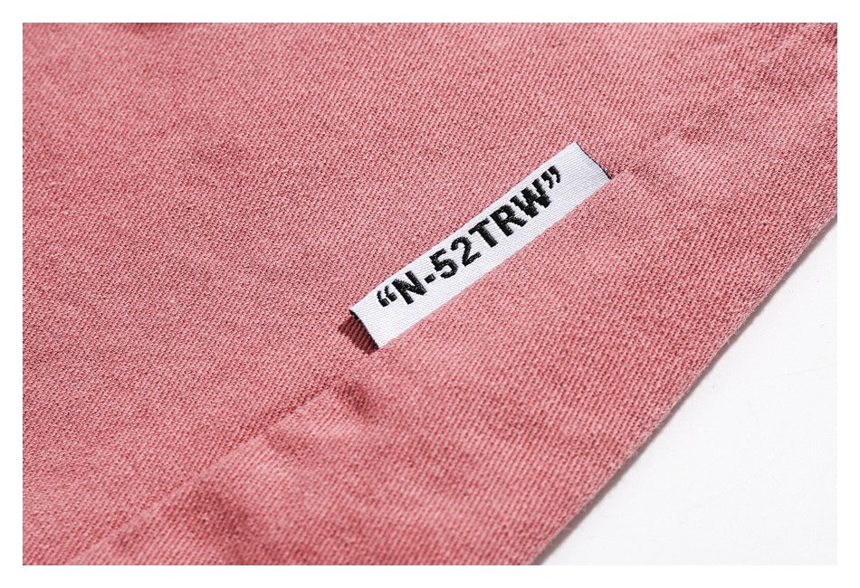 Close-up of dusty rose fabric with a small white sewn label bearing black lettering.