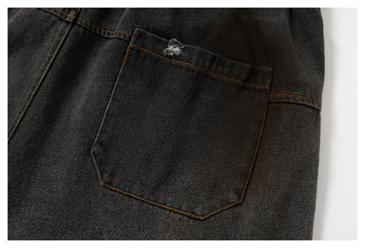 Close-up of the back pocket on charcoal-black pants, with ochre stitching and a small frayed detail.