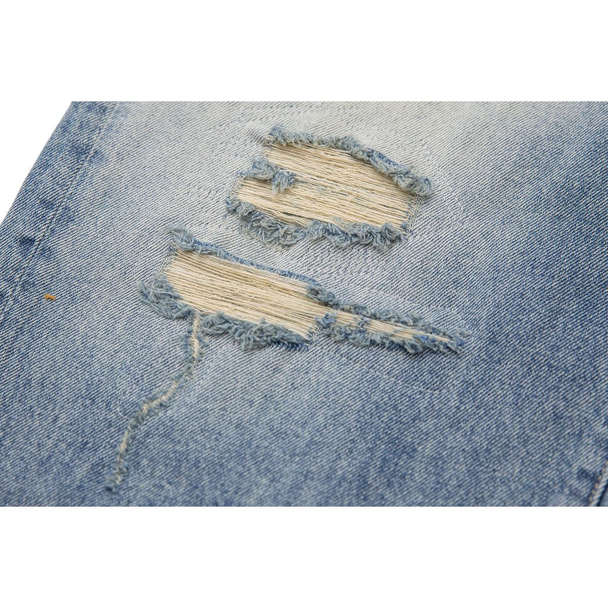 Close-up of two frayed horizontal tears in faded light-blue denim.