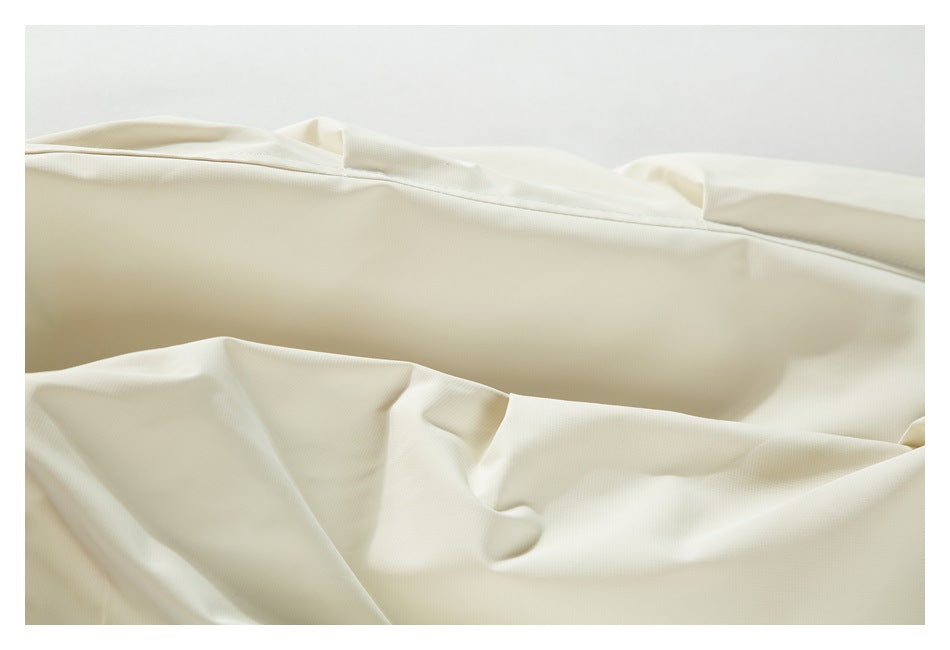 Close-up of smooth ivory fabric draped in folds, with a stitched seam near the top.