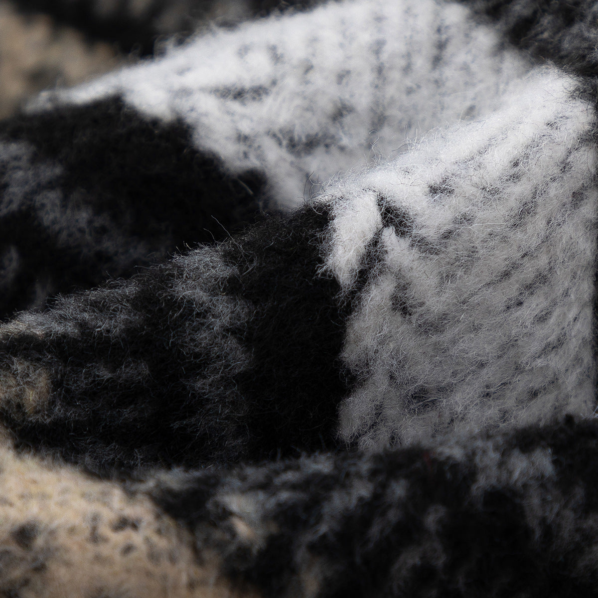 Extreme close-up of fuzzy black, gray, white, and beige plaid fabric.