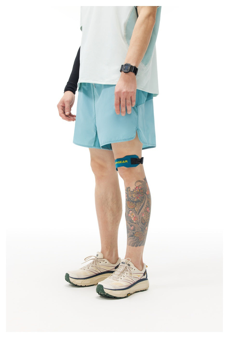 Side view of a person wearing light teal-blue shorts with a light top, leg strap and cream sneakers