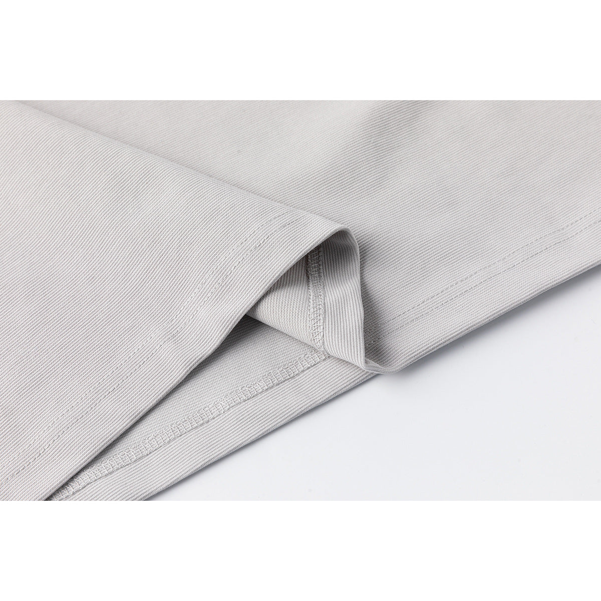 Close-up of the light gray shirt's folded hem and stitched seam.