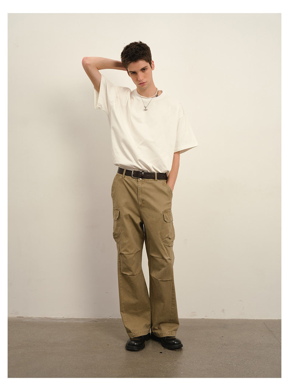 Model wearing khaki wide-leg cargo pants with flap pockets, a white T-shirt and black shoes, standing front-facing.