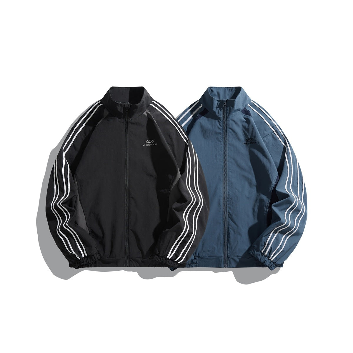 Front view of black and slate-blue zip-up track jackets with stand collars, elastic hems and white sleeve stripes.
