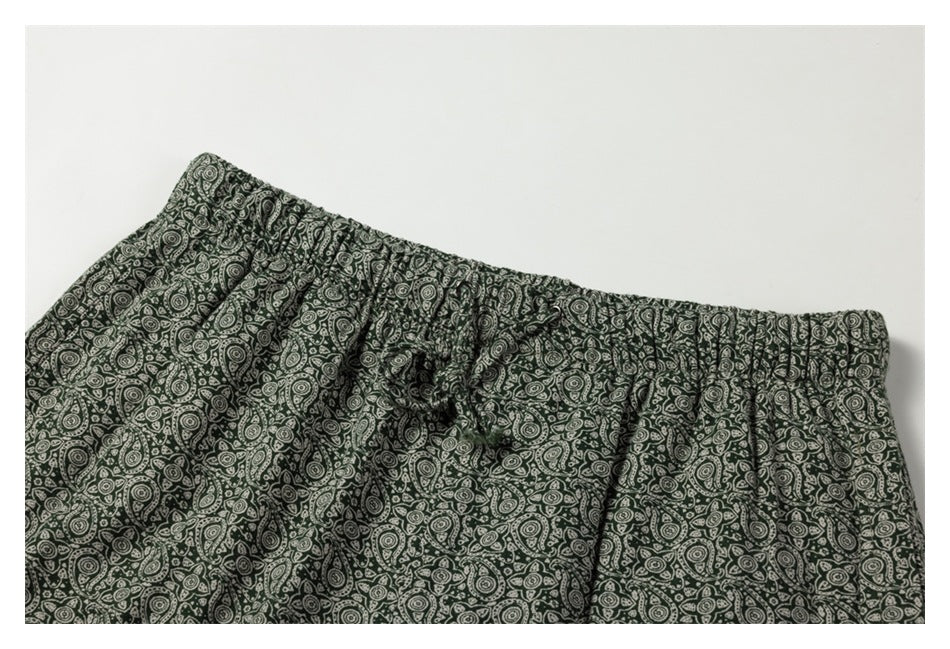 Dark green pants with a cream paisley print, shown close up at the gathered waistband and drawstring.