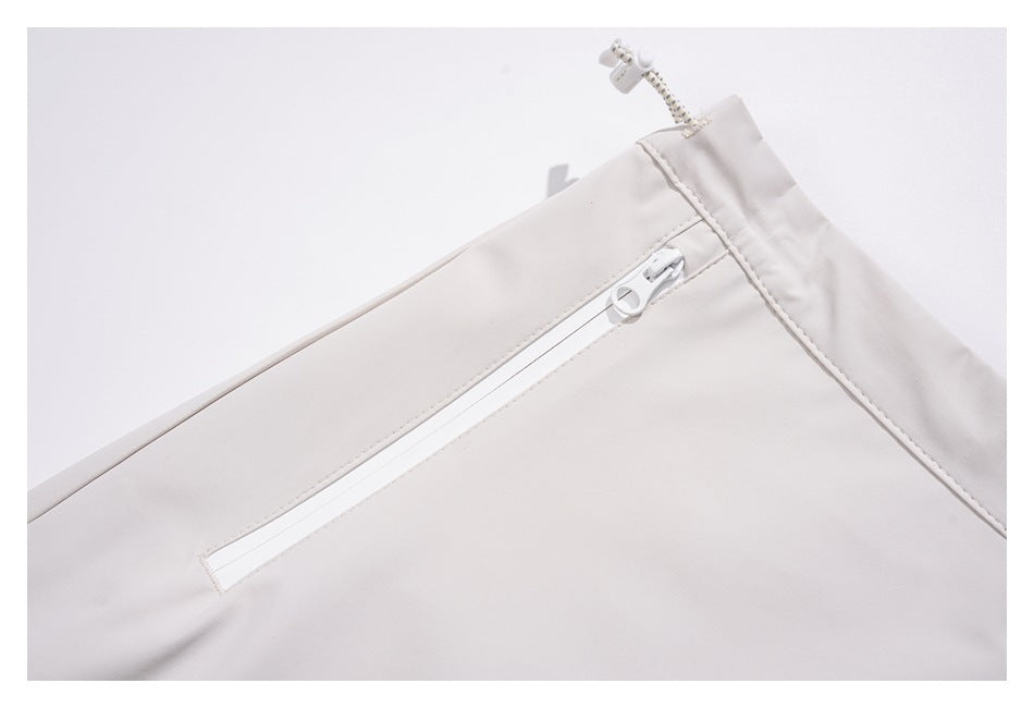 Close-up of an off-white skirt's white zip pocket and gathered waistband with drawcord.