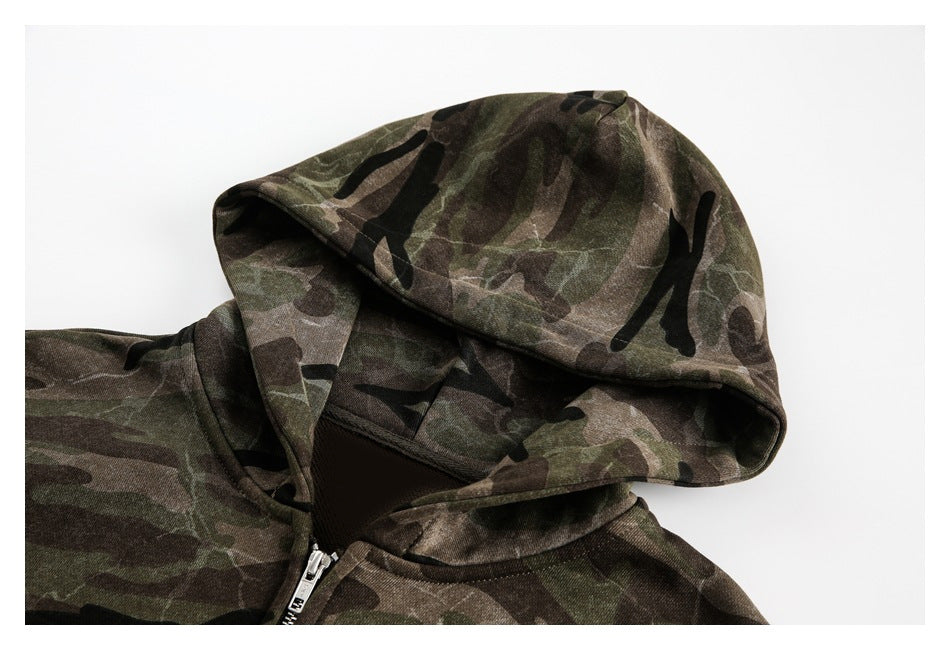 Close-up of a dark green, brown, and black camouflage hoodie showing its hood and front zipper.