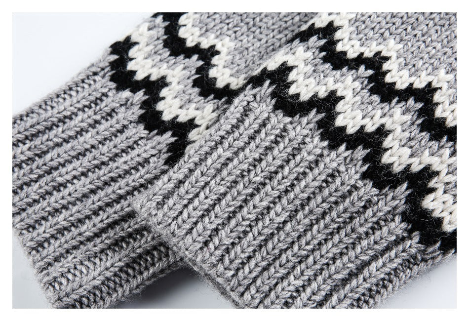 Close-up of a gray knitted sweater with black and white patterned bands and a ribbed edge.