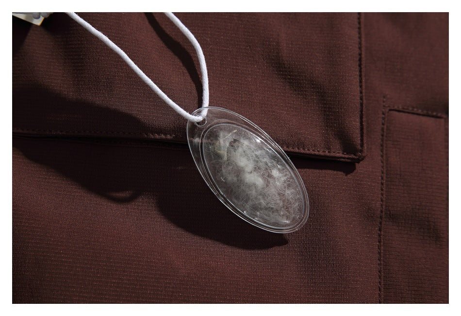 Close-up of dark brown garment fabric with a stitched pocket and a clear oval tag containing fibers.