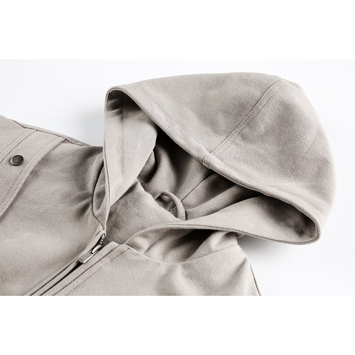 Close-up of a light taupe hooded jacket showing the hood, drawcord, zipper, and snap detail.