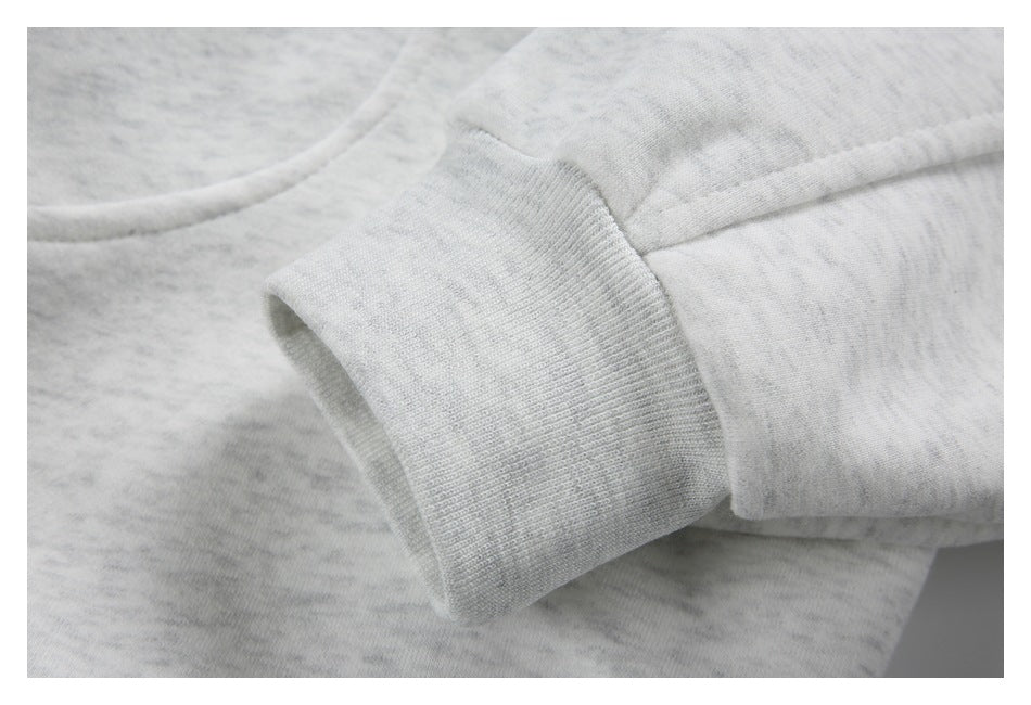 Close-up of a light gray marled garment sleeve ending in a ribbed cuff.