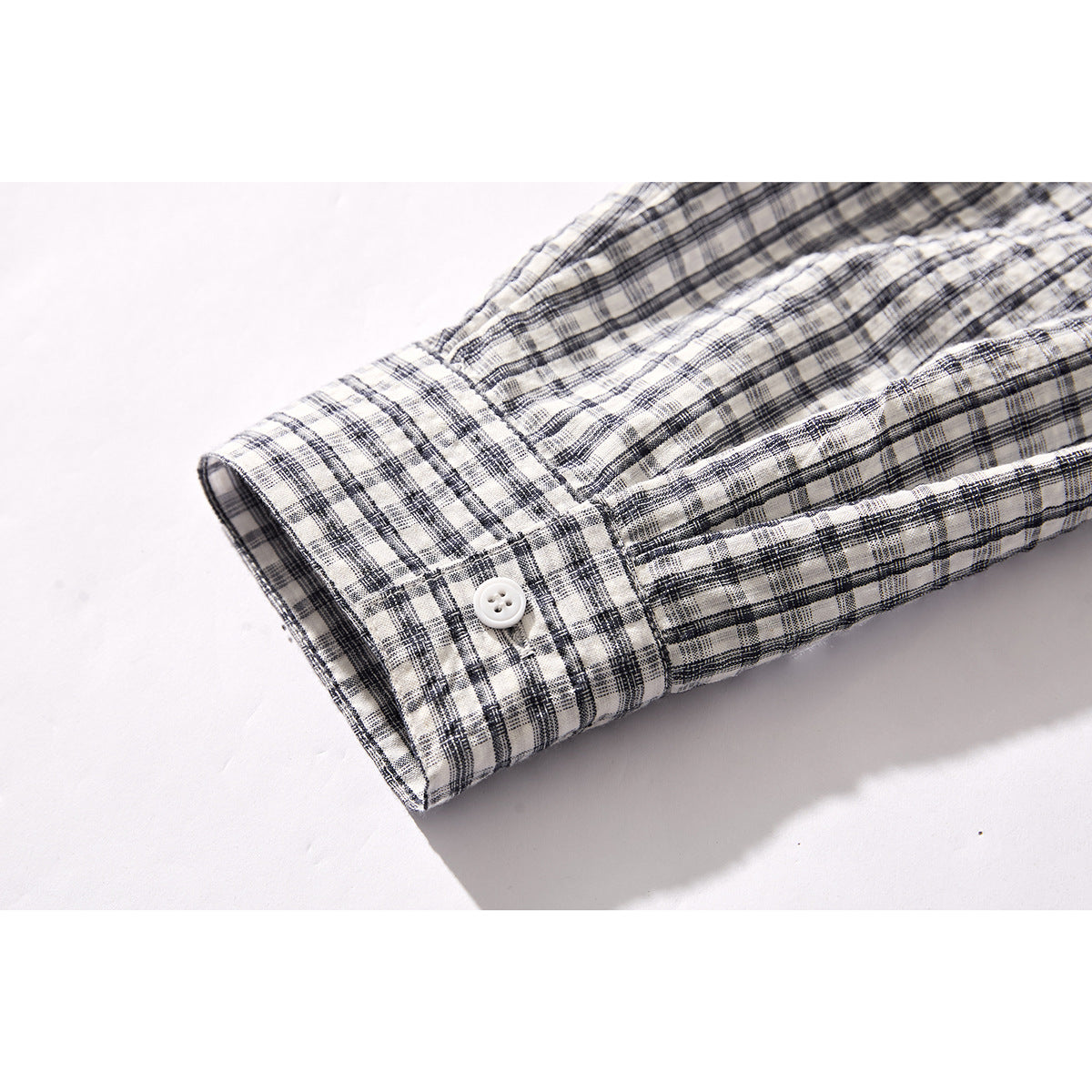 Close-up of a black-and-white plaid shirt sleeve cuff with a white button.