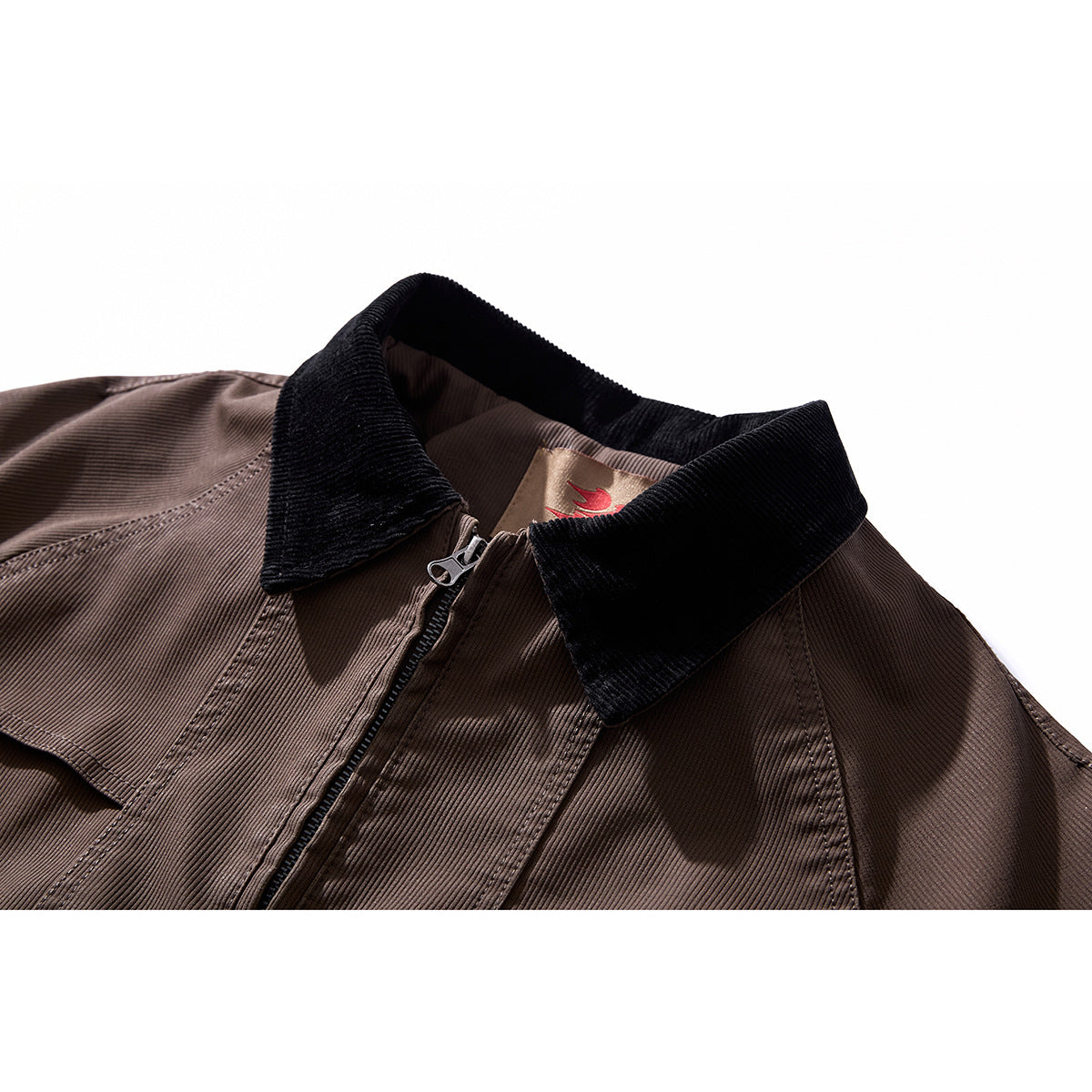 Close-up of a brown jacket with a black corduroy collar, front zipper, and stitched panels.
