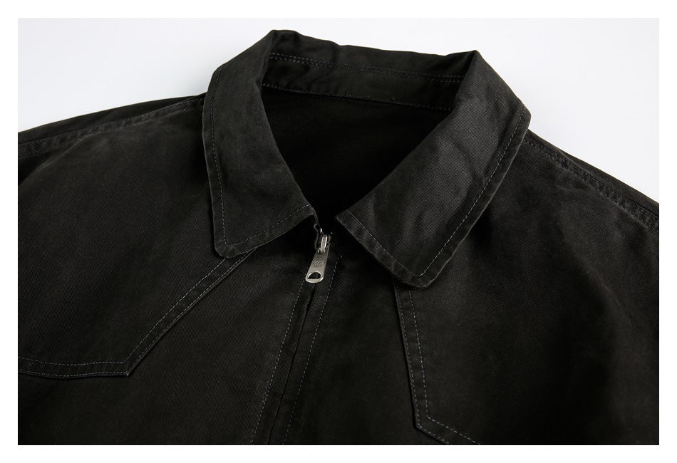 Close-up of the black jacket's pointed collar, front zipper, and angular stitched chest panels.