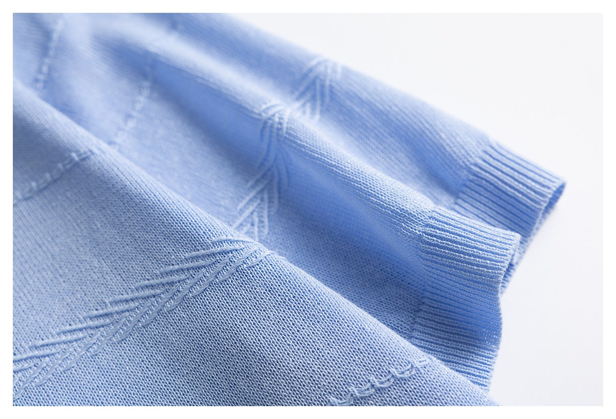 Close-up of light blue knit fabric showing raised decorative seams and a ribbed edge.
