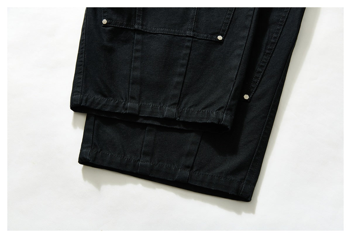 Close-up of black trouser legs showing a stitched pocket and finished hems.
