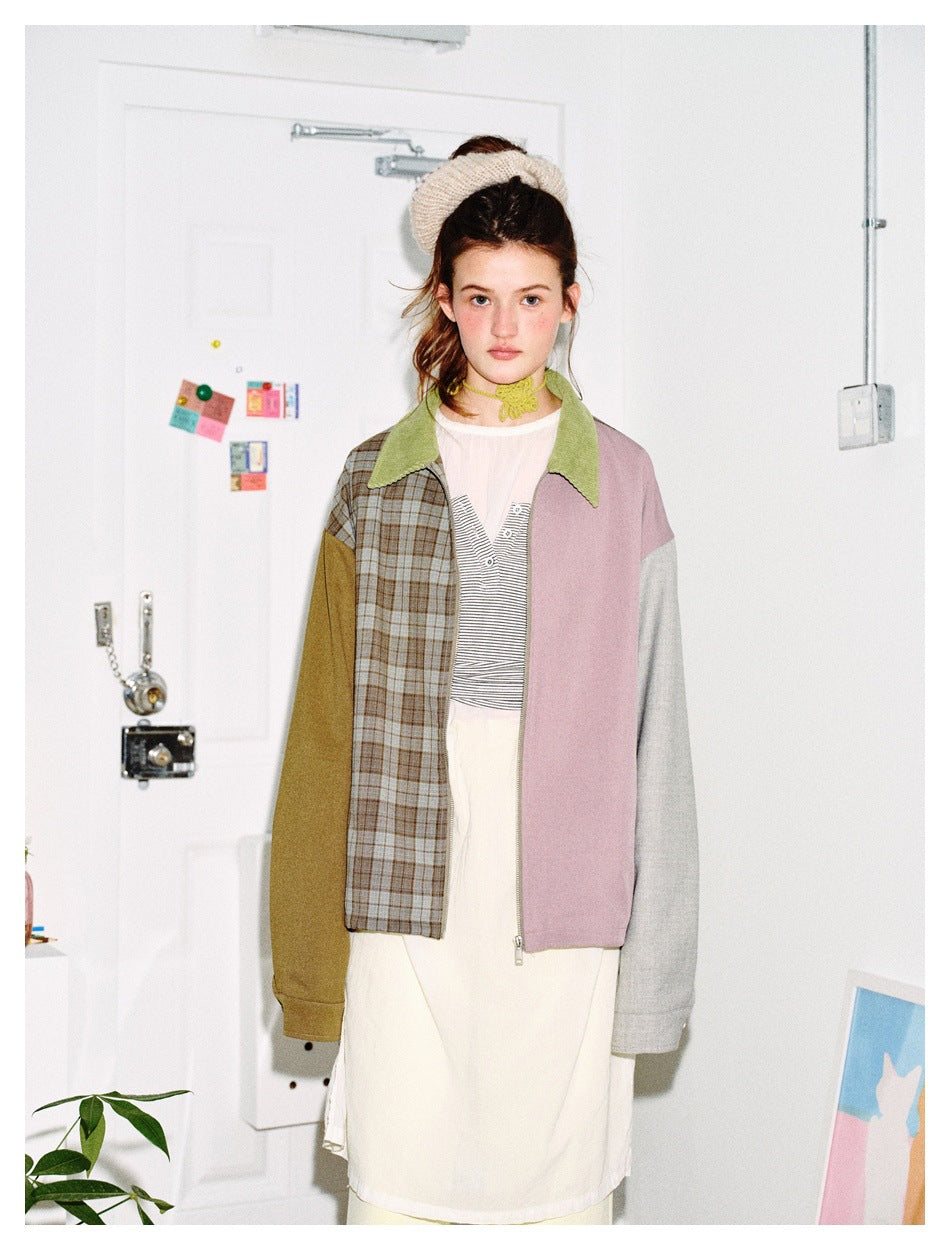 Front view of a model wearing a color-block jacket with a plaid panel, olive and gray sleeves, pink panel, and green collar.