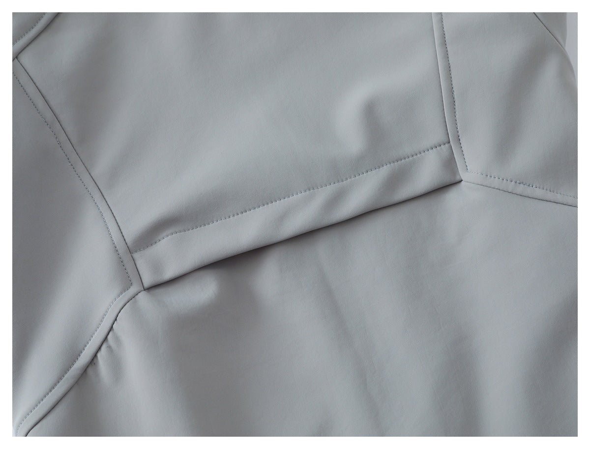 Close-up of light gray garment fabric with curved panel seams and visible stitching.