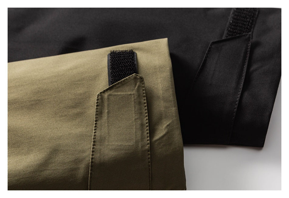 Close-up of olive-khaki and black jacket fabric showing a hook-and-loop cuff tab.