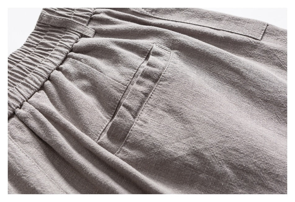 Close-up of the elastic waistband and pocket stitching on light gray trousers.