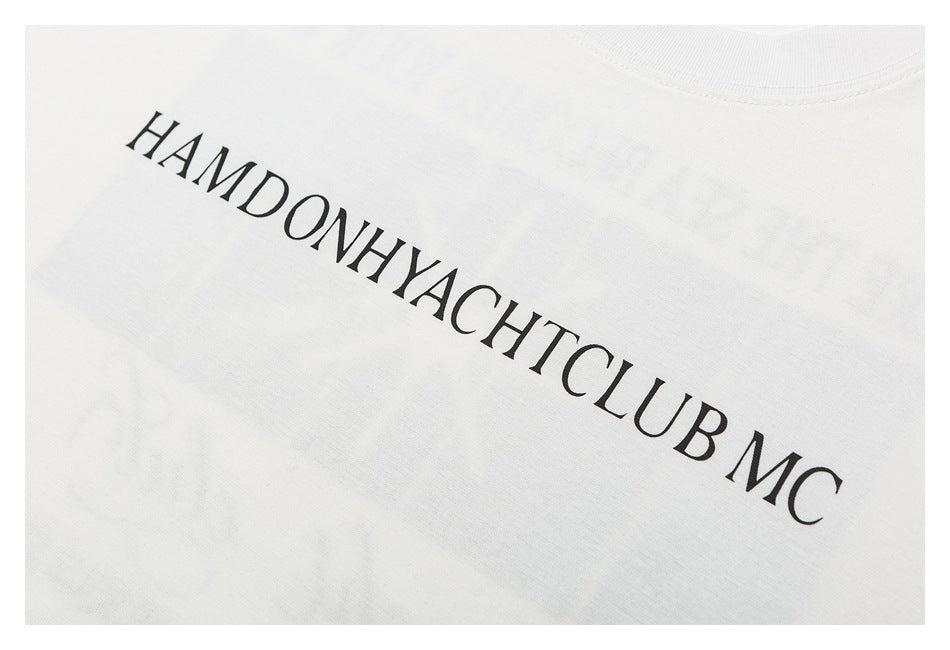 Close-up of black “HAMDONHYACHTCLUB MC” lettering printed on an off-white T-shirt.
