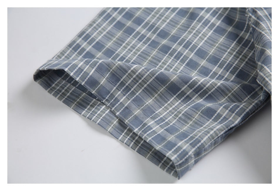 Close-up of the plaid jacket's stitched hem and folded edge.
