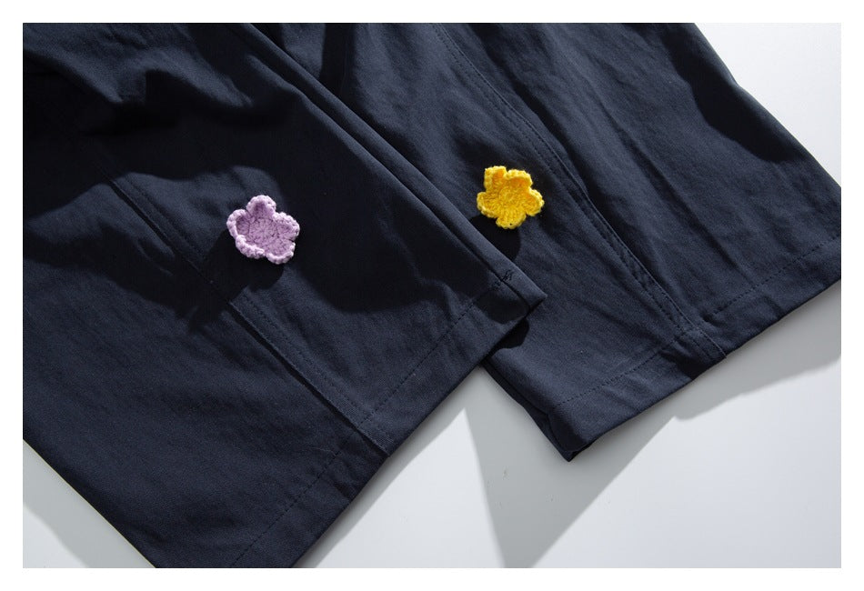 Close-up of dark navy garment hems with small lavender and yellow crocheted flower details.
