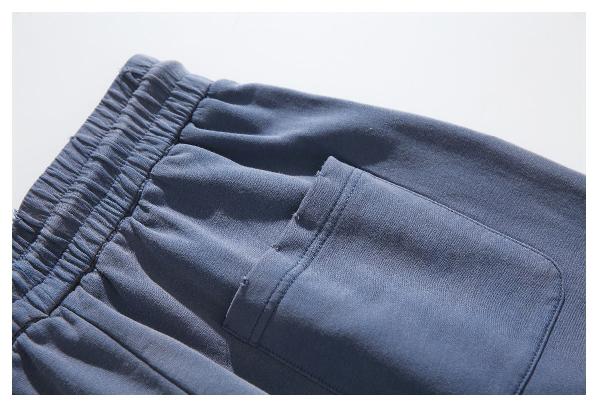 Close-up of a large patch pocket and gathered waistband on navy pants.