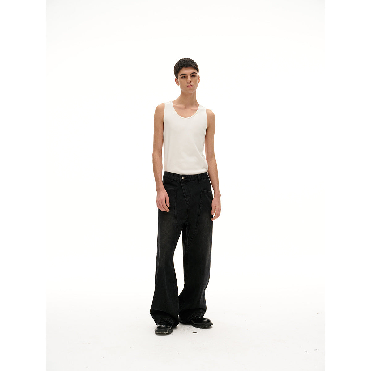 Full-length model facing forward in a white tank top, loose black wide-leg jeans, and black shoes.