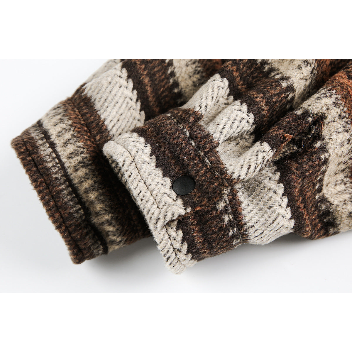 Close-up of the plaid overshirt cuff, showing its folded edge and black snap closure.