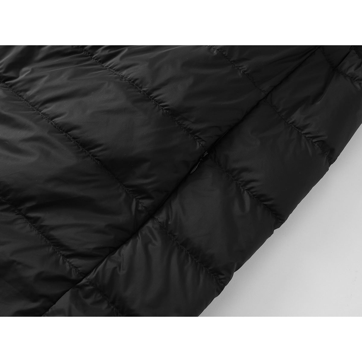 Close-up of black quilted vest fabric, stitched panels, and a small side zipper.