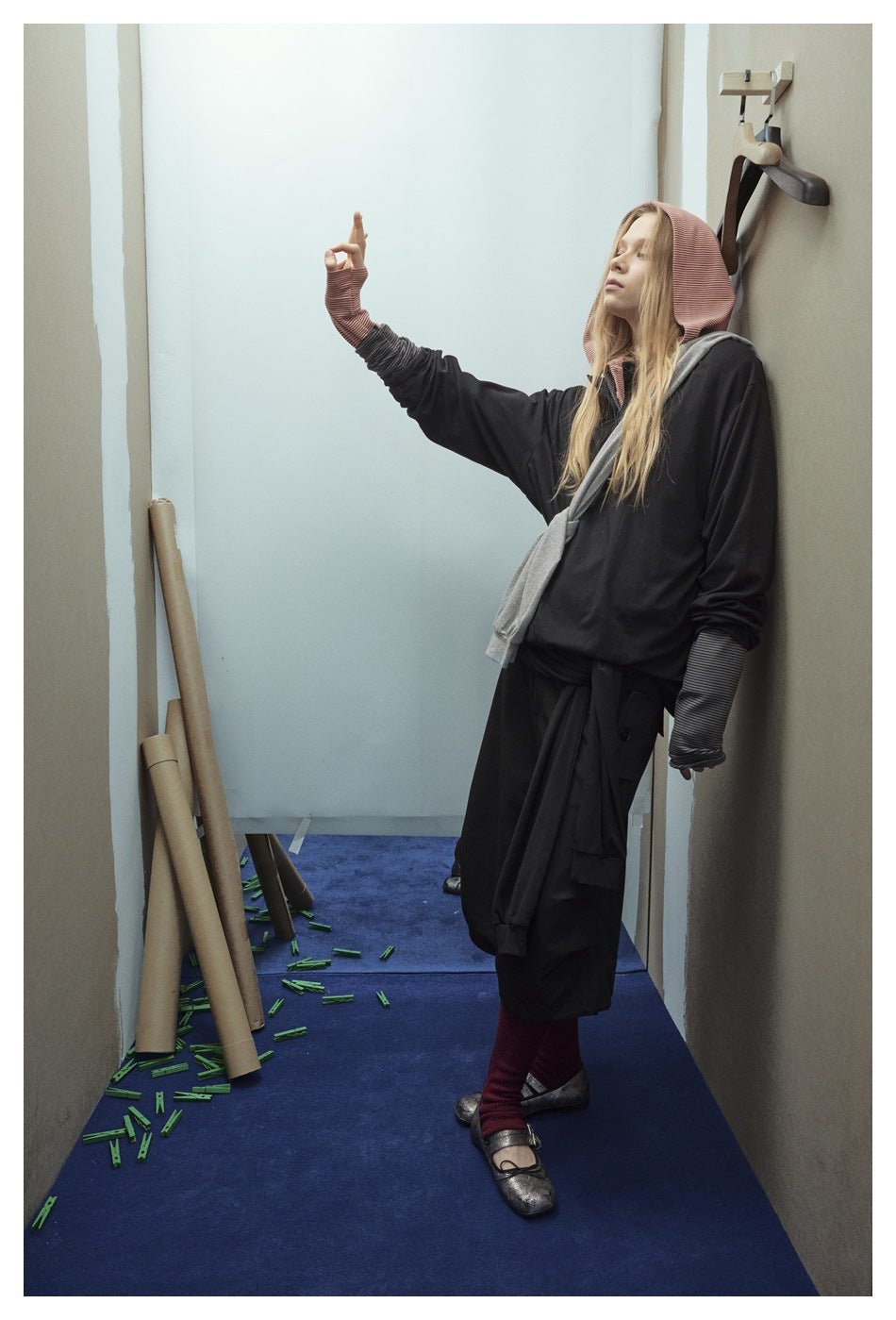 Model in profile wearing a black hooded top with contrasting striped hood and cuffs, gray layer, and black bottoms.