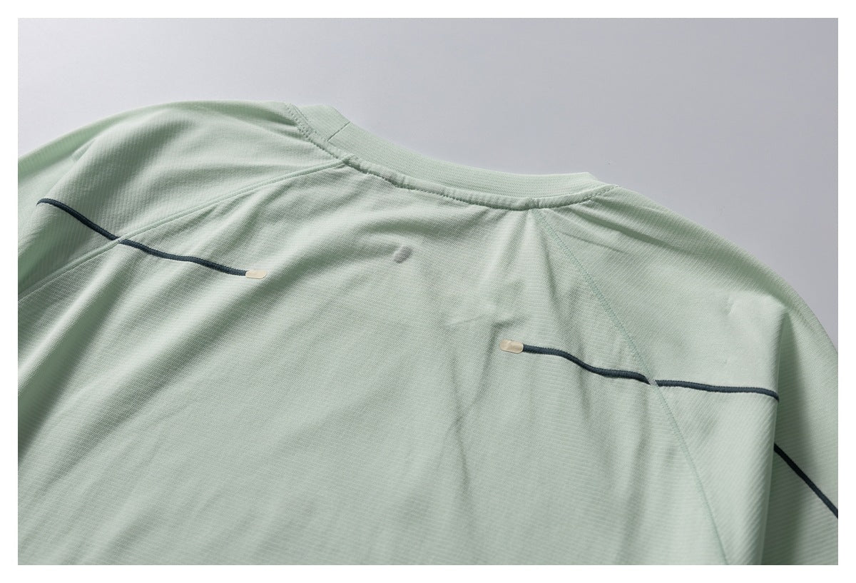 Close-up of the upper back of a pale mint-green top with dark horizontal piping and small beige tabs.