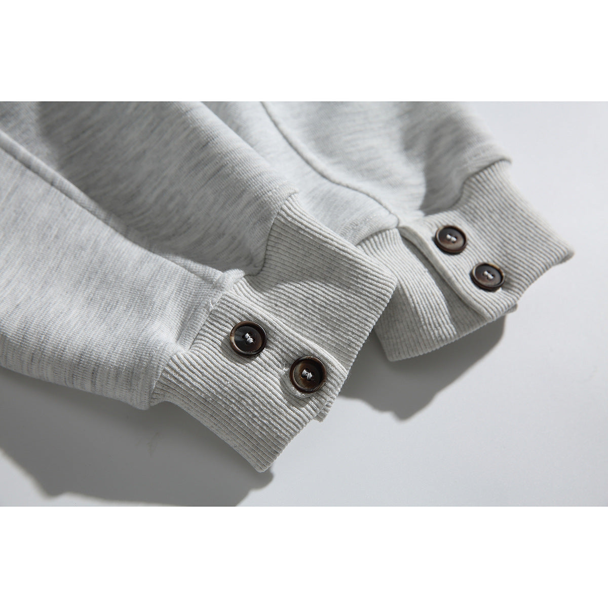 Close-up of the light gray cardigan’s ribbed cuffs and dark cuff buttons.