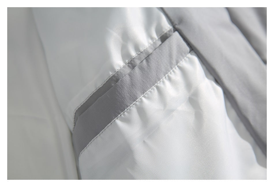 Close-up of a light gray jacket's shiny inner lining and stitched seam.