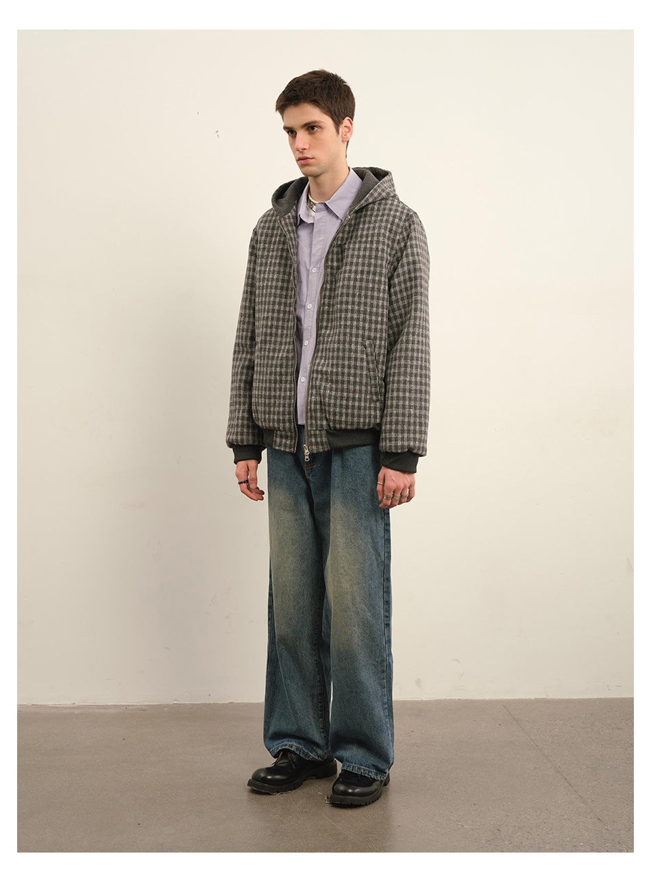 Model wearing a gray check hooded zip jacket with dark ribbed trim and loose blue jeans.