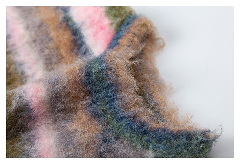 Close-up of a folded edge of fuzzy striped fabric in brown, blue, olive, pink, and cream.