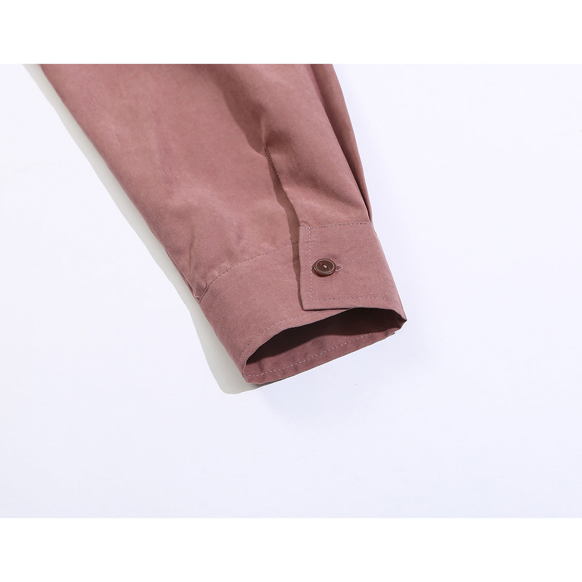 Close-up of a dusty mauve shirt sleeve ending in a buttoned cuff.
