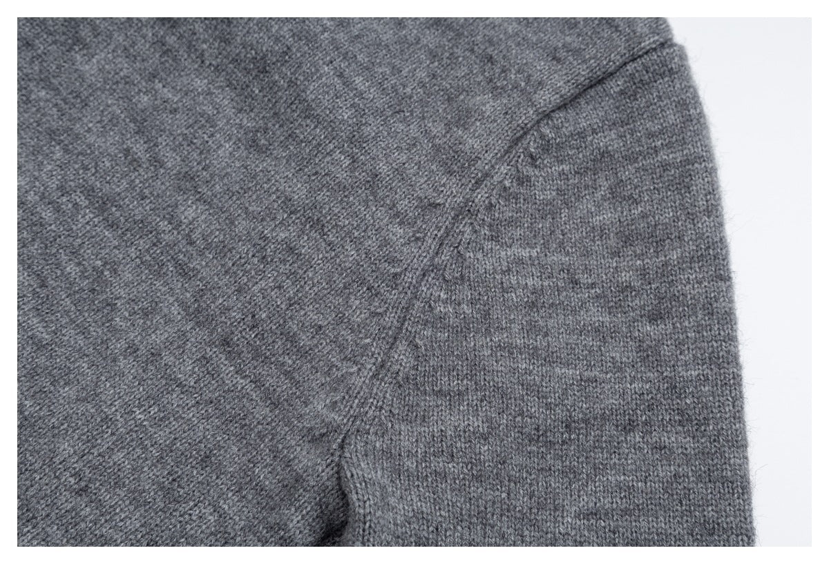 Close-up of gray knit garment fabric showing a curved seam and fine stitch texture.