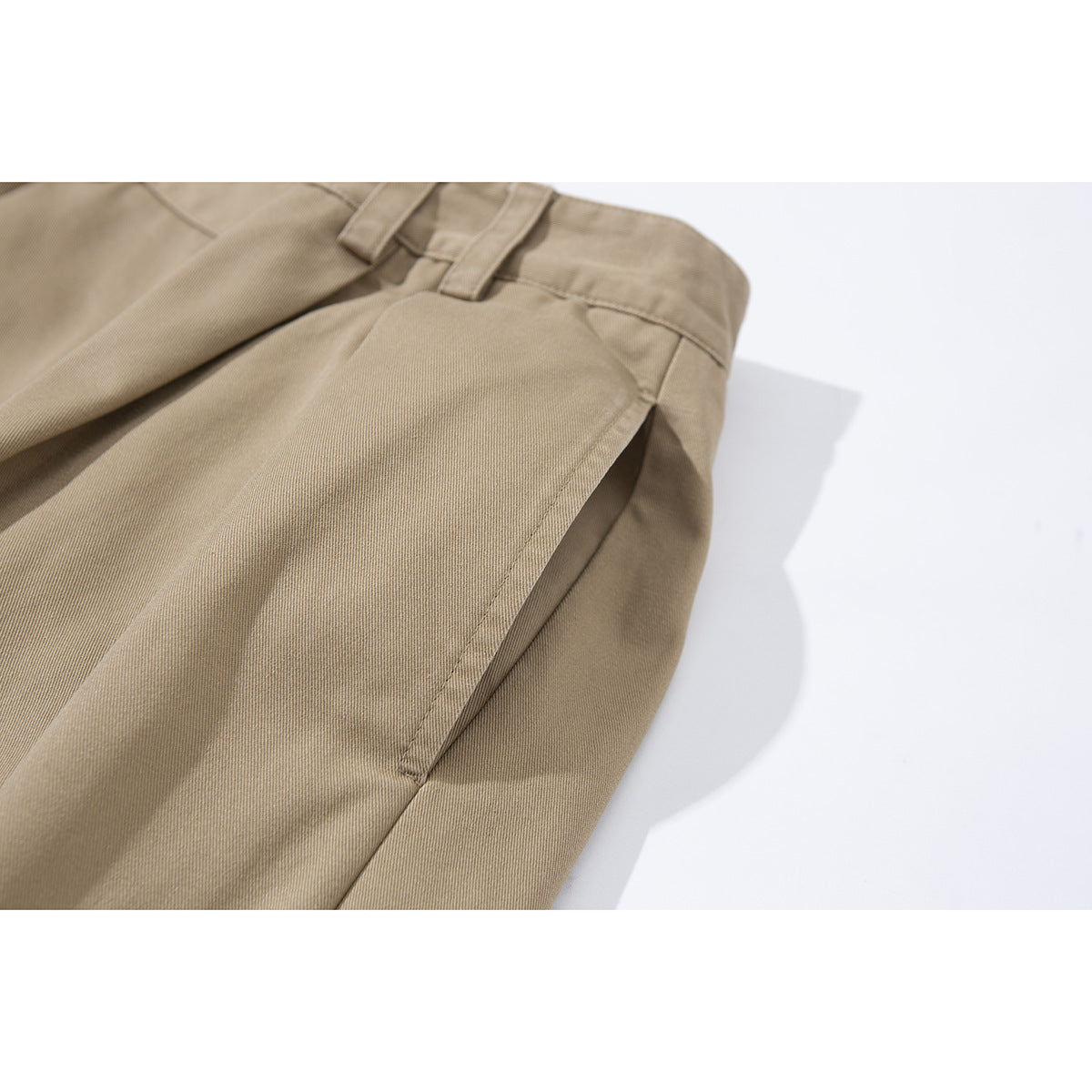 Angled close-up of tan shorts showing a front pocket, belt loops and waistband.