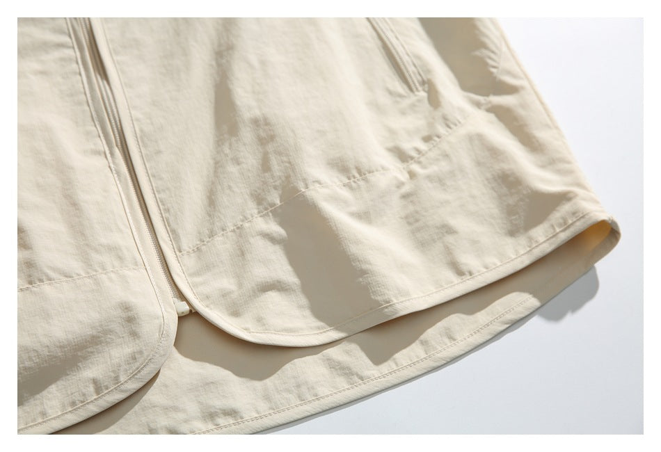 Close-up of the light beige jacket's curved front hem and zipper.