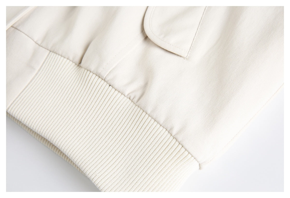 Close-up of an ivory jacket's ribbed hem and lower pocket area.