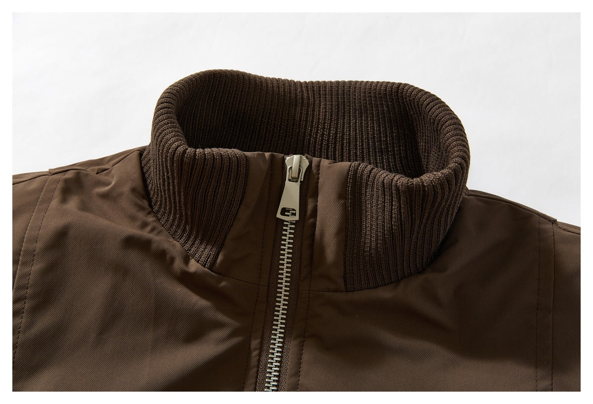 Close-up of the brown jacket's dark ribbed stand collar and silver front zipper.