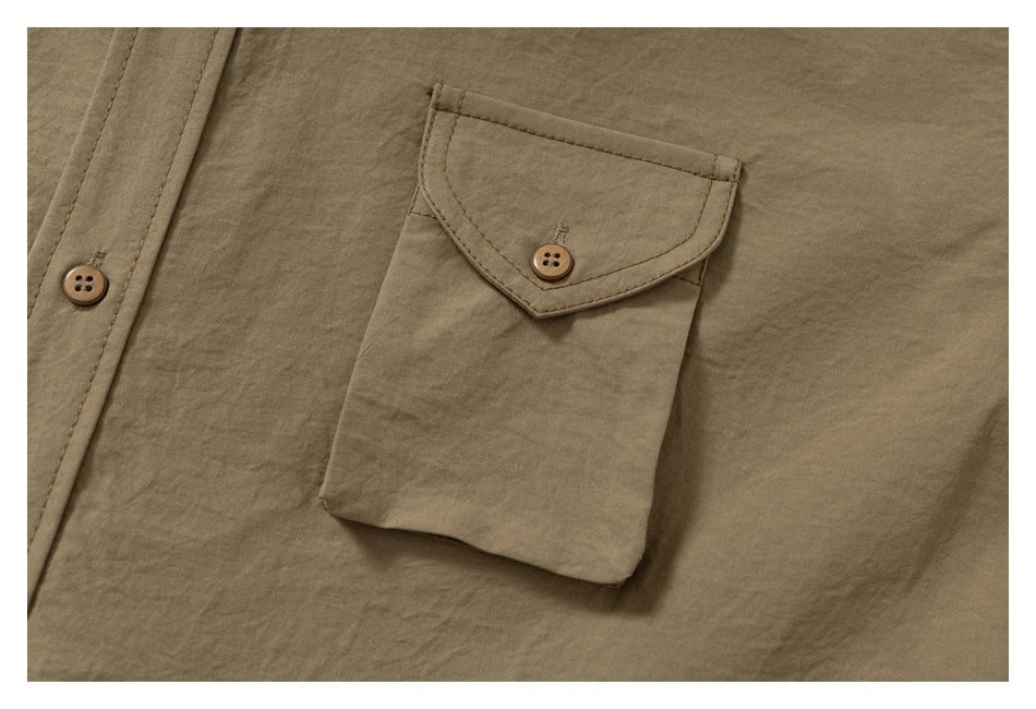 Close-up of a tan shirt's buttoned flap chest pocket and front placket.
