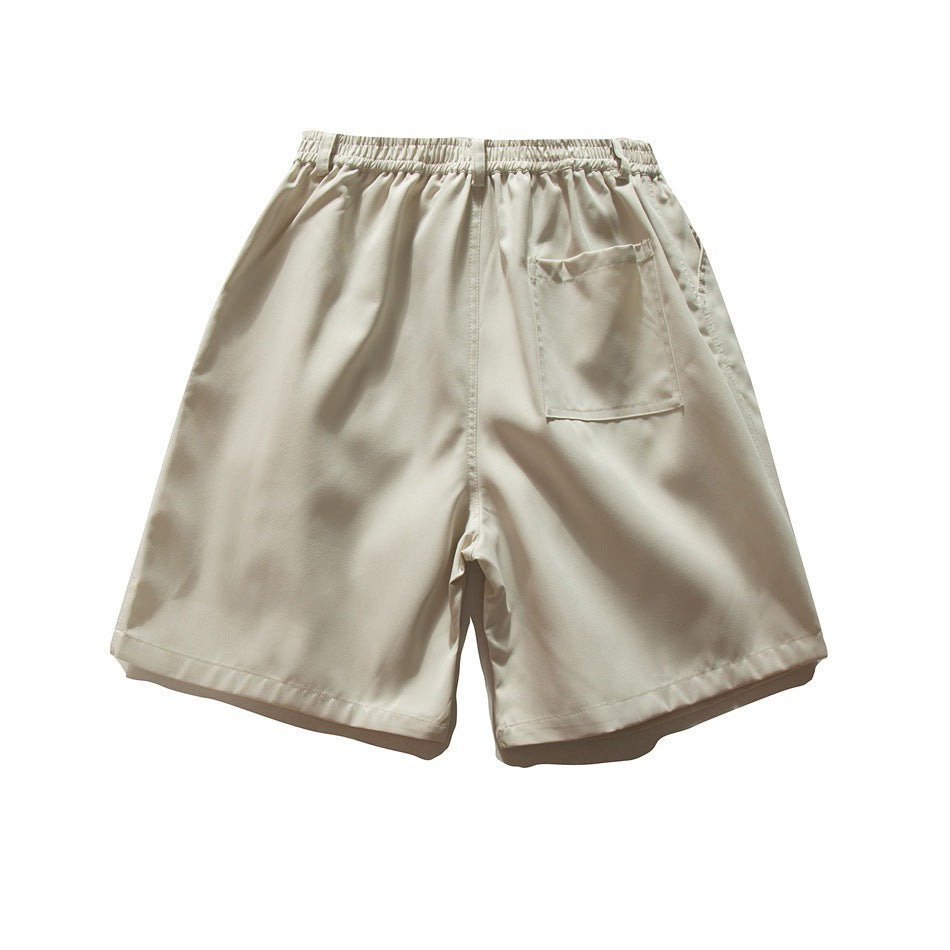 Back view of light beige shorts with an elastic waistband and a single rear patch pocket.