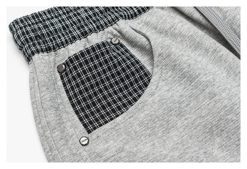 Close-up of a heather-gray pants pocket with a black-and-white plaid panel and small metal buttons.