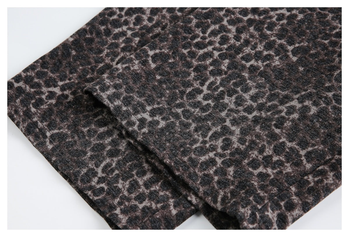 Folded section of dark leopard-print garment fabric, showing a stitched edge and overlapping layers.