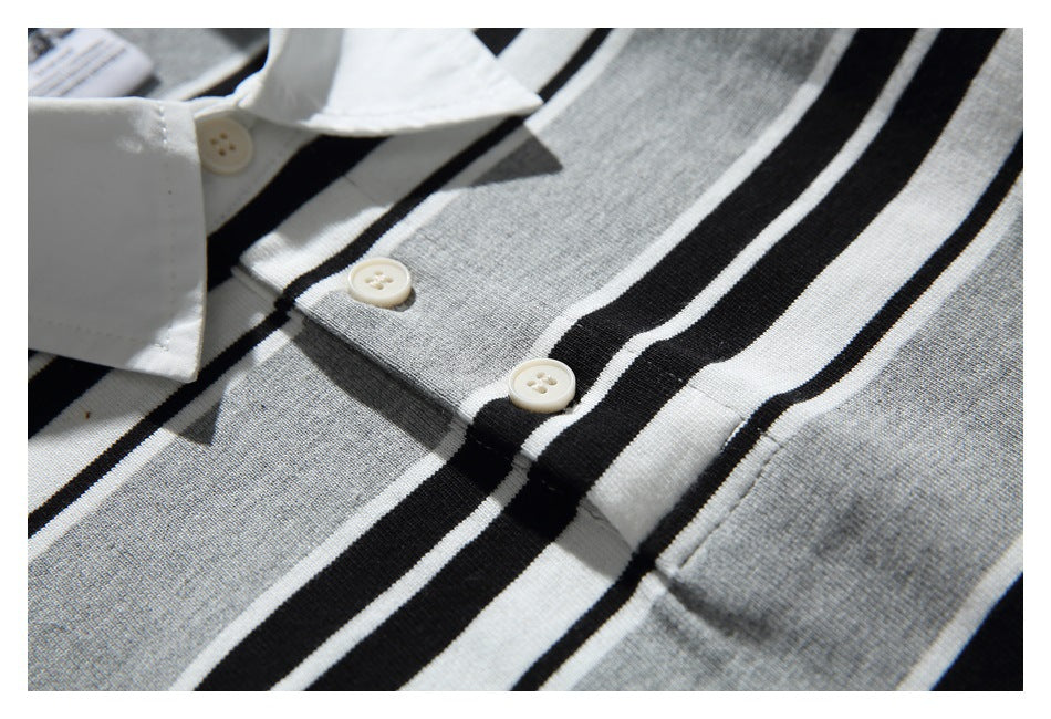 Close-up of two cream-colored buttons and the placket against the shirt's gray, black, and white stripes.