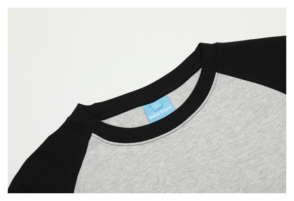 Close-up of a heather gray raglan T-shirt's black neckline and shoulder seam, with a blue neck label.